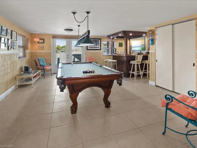 Rec room with bar, pool table, french doors, and light tile patterned flooring