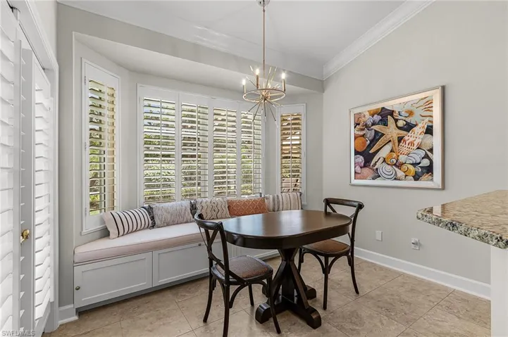 Dining space with ornamental molding, a chandelier, and light tile patterned floors