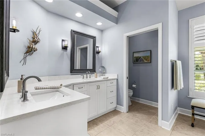 Bathroom with double vanity, light tile patterned flooring, and recessed lighting