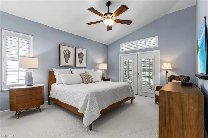 Bedroom featuring lofted ceiling, access to exterior, multiple windows, french doors, and a ceiling fan