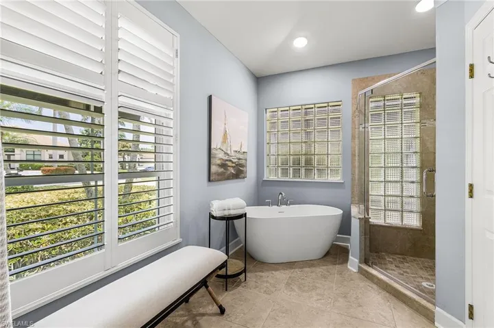 Bathroom with a shower stall, a freestanding tub, plenty of natural light, and light tile patterned flooring