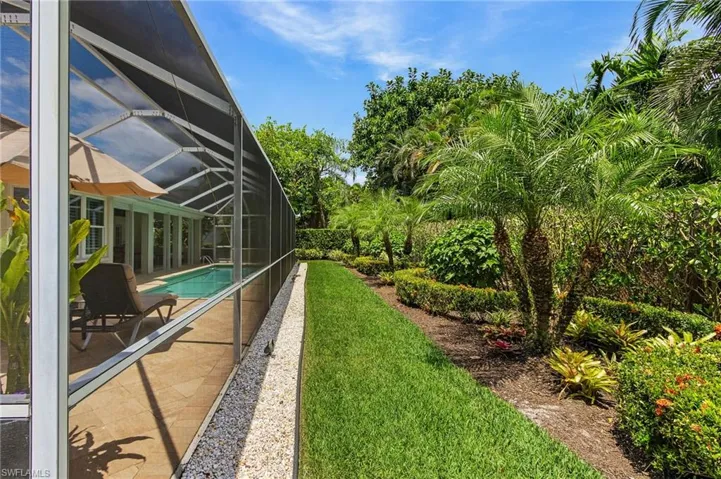 View of grassy yard with glass enclosure, a sunroom, an outdoor pool, and a patio area