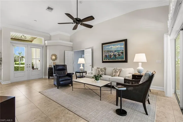Living room with lofted ceiling, french doors, ceiling fan, light tile patterned floors, and crown molding