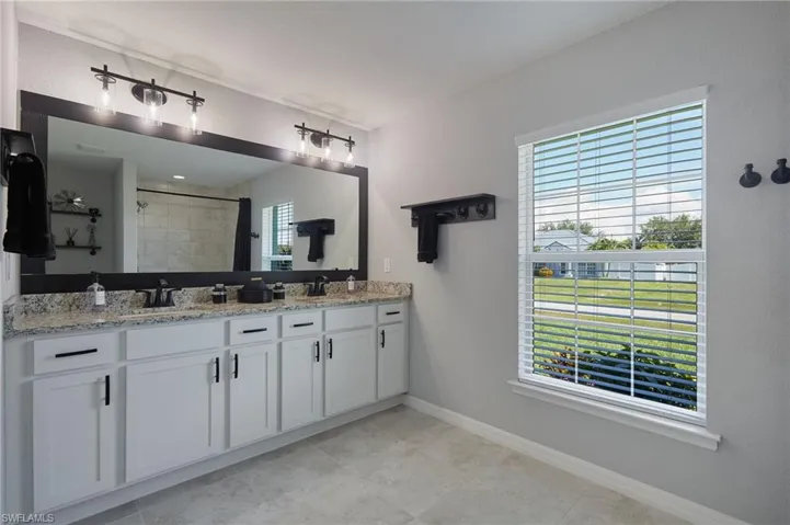 Full bath with double vanity, a tile shower, and plenty of natural light