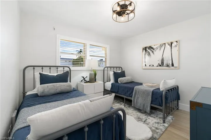 En-suite guest Bedroom setup with twin beds, custom light fixtures, and adorned with Plantation shutters