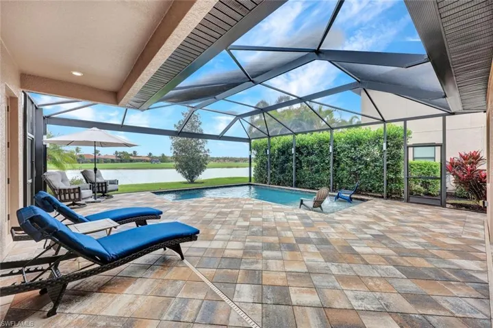 Outdoor pool with a lanai, a patio area, a sunroom, and a water view