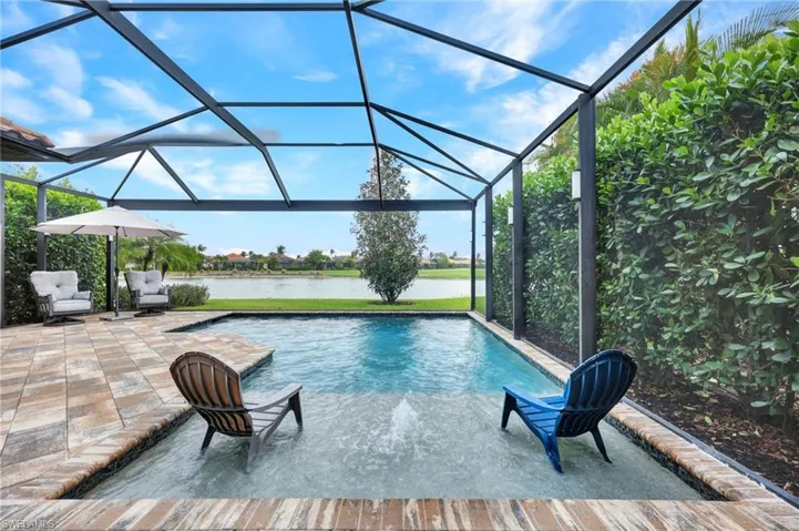 Swimming pool featuring glass enclosure, a sunroom, and a water view