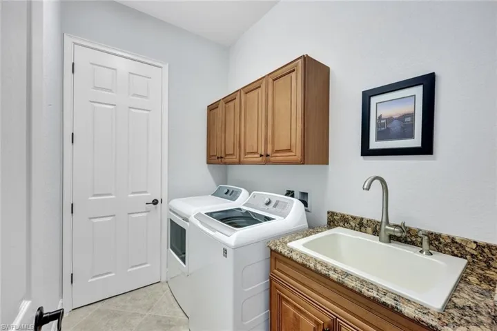Laundry area featuring cabinet space, light tile patterned floors, and washer and dryer