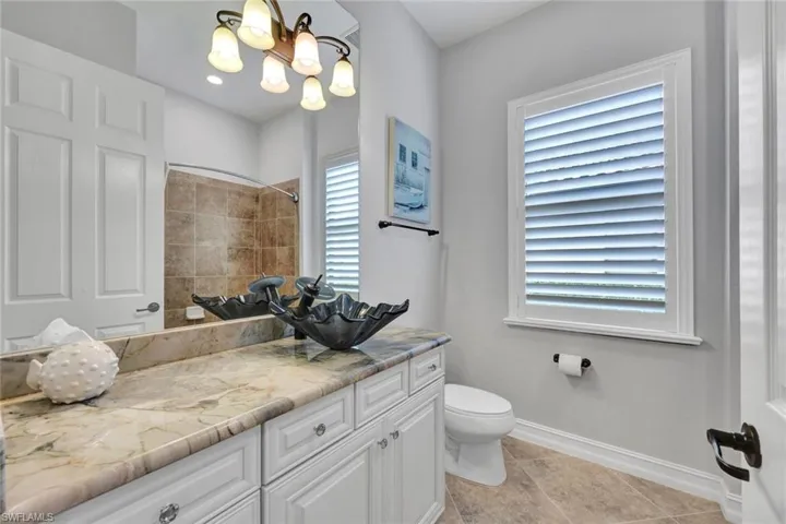 Bathroom featuring vanity, light tile patterned floors, a shower, and a chandelier