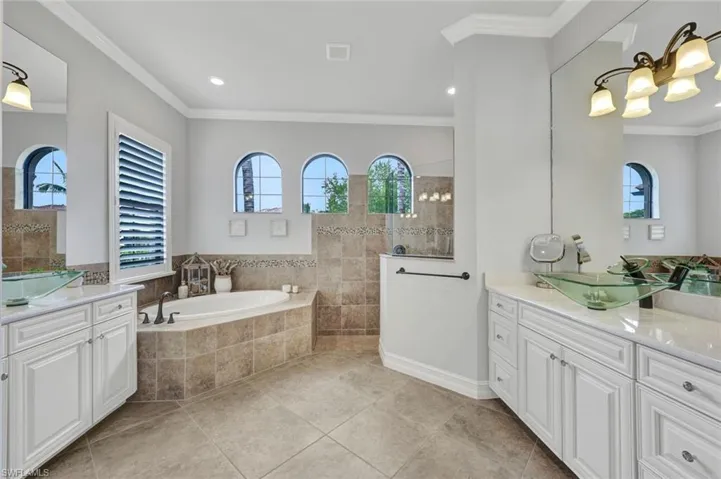 Bathroom featuring crown molding, two vanities, walk in shower, plenty of natural light, and recessed lighting