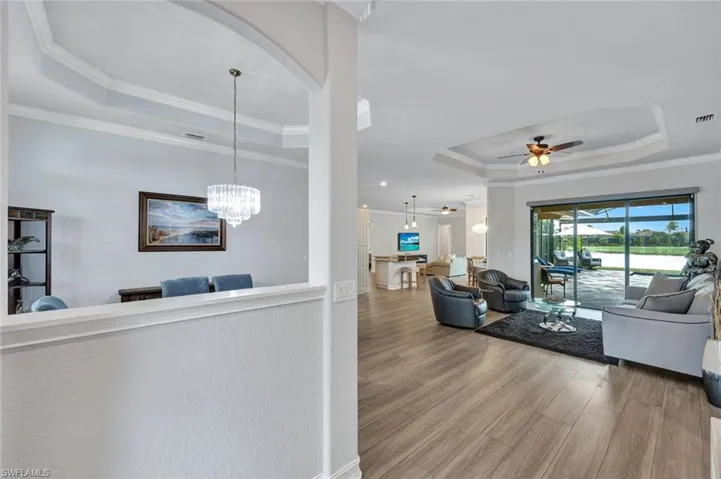 Living area with a tray ceiling, ornamental molding, wood finished floors, and ceiling fan
