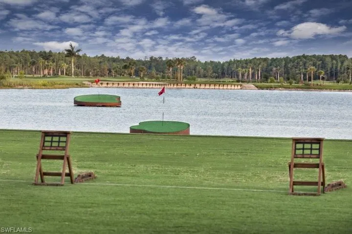 View of home's community with a water view and a putting green
