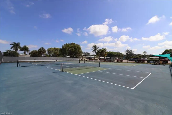 View of tennis court featuring community basketball court and fence