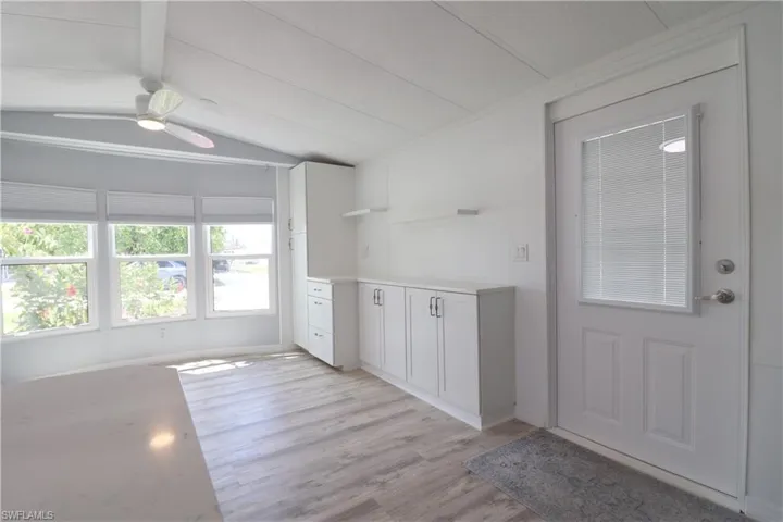 Kitchen with a ceiling fan, white cabinetry, open shelves, light wood-style floors, and vaulted ceiling