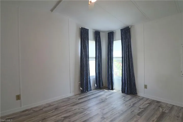 Unfurnished room featuring vaulted ceiling with beams and wood finished floors