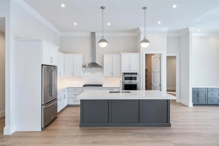 The kitchen features KitchenAid appliance suite with natural gas cooking, Pompeii quartz cabinetry, and a walk-in pantry.