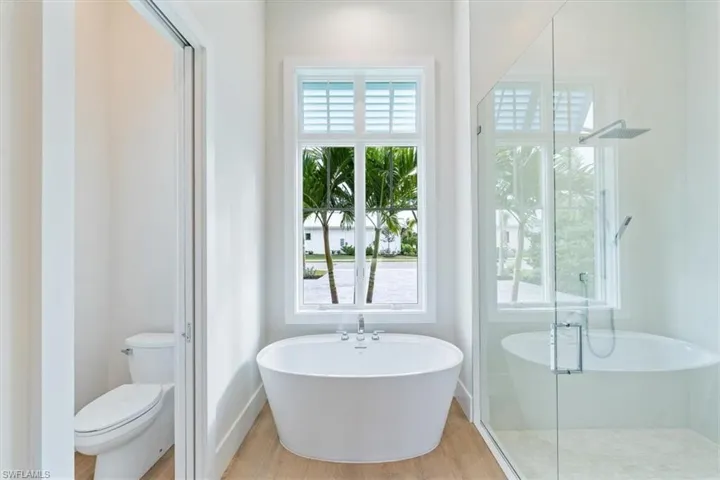 The primary suite features 10' sliders out to the pool deck, dual walk-in closets, and a spa bathroom with shower, free standing soaking tub, private WC, and two sinks.
