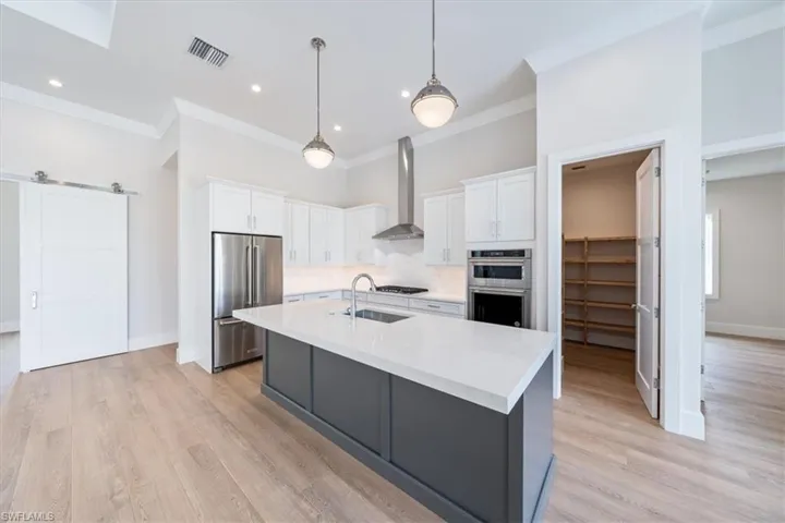 The kitchen features KitchenAid appliance suite with natural gas cooking, Pompeii quartz cabinetry, and a walk-in pantry.