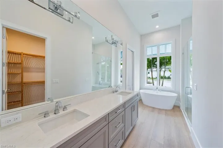 The primary suite features 10' sliders out to the pool deck, dual walk-in closets, and a spa bathroom with shower, free standing soaking tub, private WC, and two sinks.