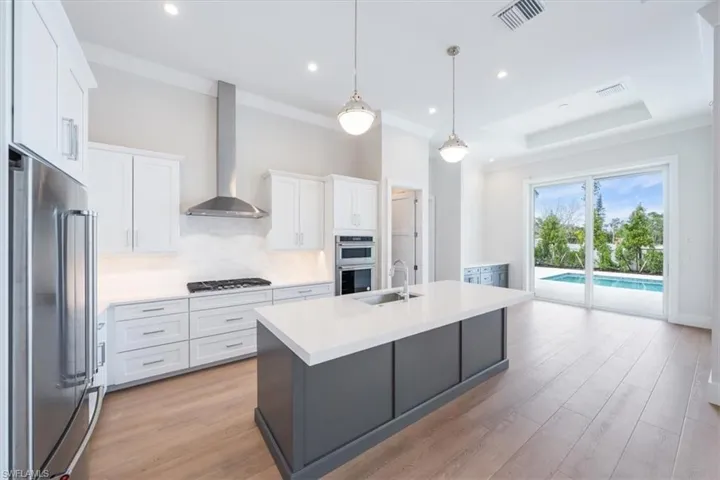 The kitchen features KitchenAid appliance suite with natural gas cooking, Pompeii quartz cabinetry, and a walk-in pantry.