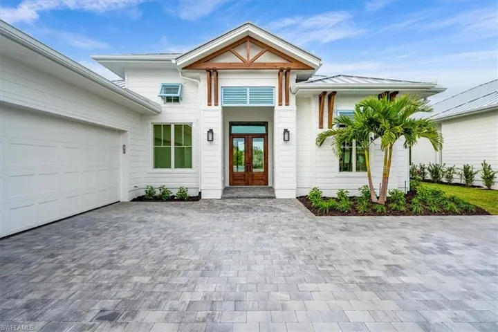 4506 features light blue Bahama shutters and natural wood accents against crisp white paint and standing-seam metal roofing.