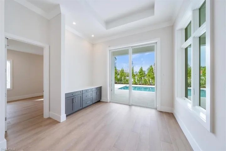 The dining room is adjacent to the kitchen and features a dry bar with ample storage and large picture windows overlooking the pool.