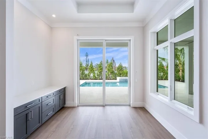 The dining room is adjacent to the kitchen and features a dry bar with ample storage and large picture windows overlooking the pool.