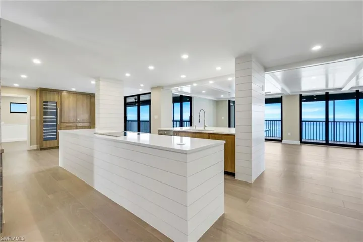 Kitchen with ornate columns, a spacious island, modern cabinets, brown cabinetry, and floor to ceiling windows