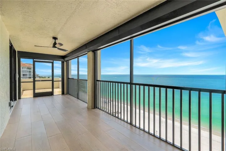 Sunroom with a ceiling fan and view of water and beach