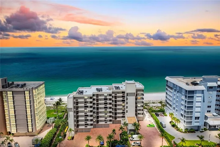 Aerial view at dusk of view of water and beach and a view of apartment building / complex