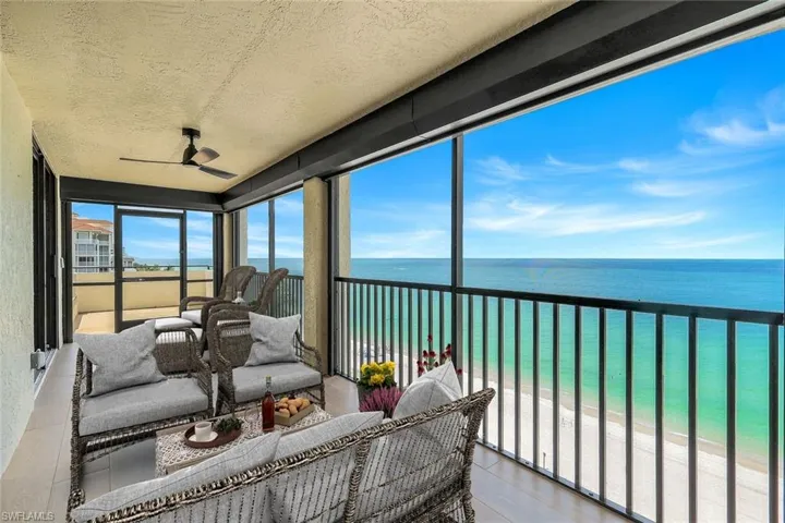 Sunroom / solarium featuring view of water and beach, a textured ceiling, and wood finished floors