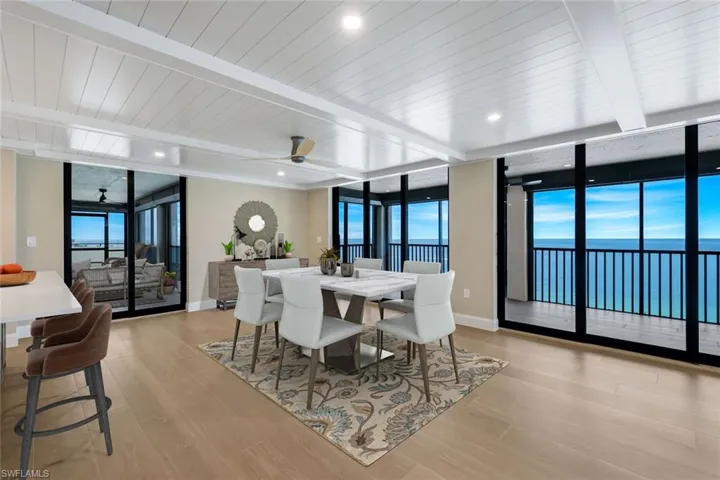 Dining area featuring expansive windows, plenty of natural light, a ceiling fan, light wood finished floors, and a water view