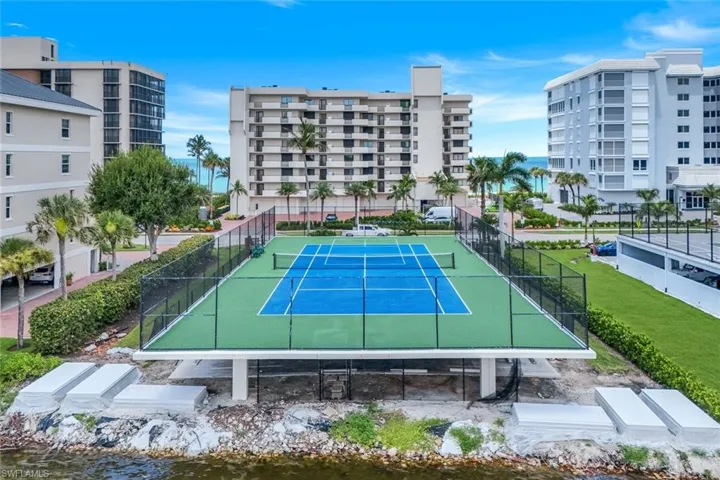 View of tennis court with a water view