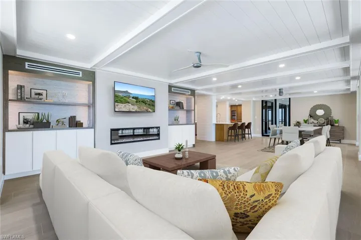 Virtually Stagged - Living area featuring light wood finished floors, ceiling fan, recessed lighting, and a wood ceiling with exposed beams