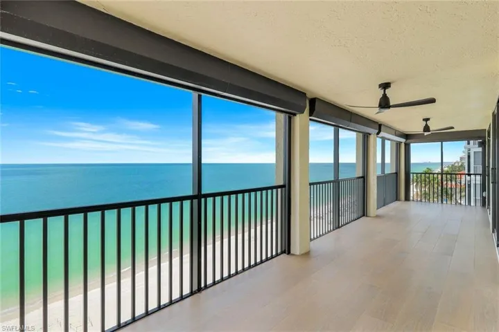 Sunroom featuring a textured ceiling, a water view, wood finished floors, and floor to ceiling windows