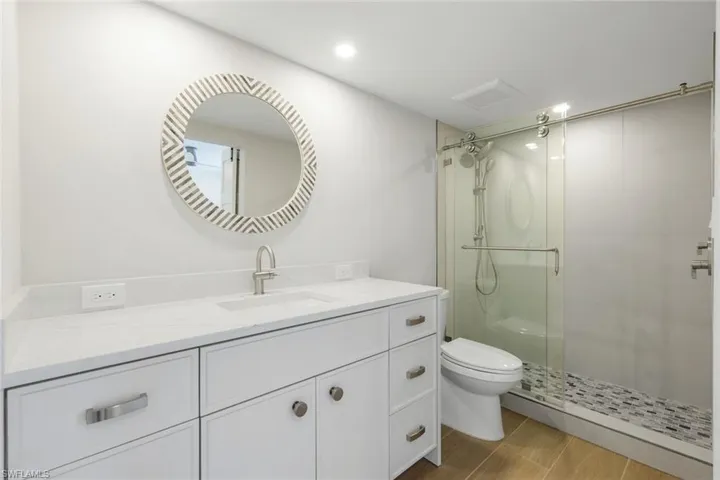 Full bathroom with a shower stall, vanity, and wood finished floors