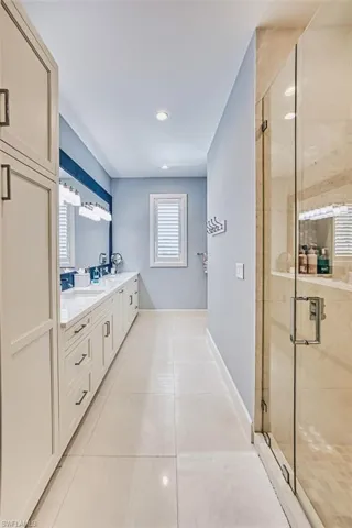 Bathroom featuring double vanity, tile patterned flooring, a stall shower, and recessed lighting