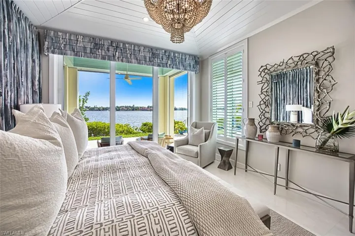 Tiled bedroom with a water view, a chandelier, and wooden ceiling
