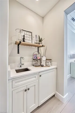 Indoor wet bar with baseboards and light wood-style flooring