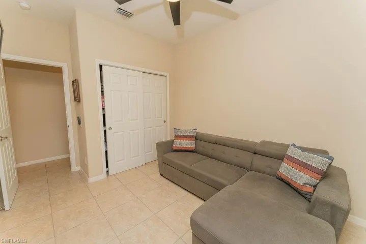Living room with ceiling fan, light tile patterned flooring, and baseboards