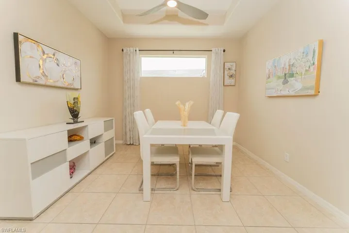 Dining space featuring a raised ceiling, light tile patterned flooring, and ceiling fan