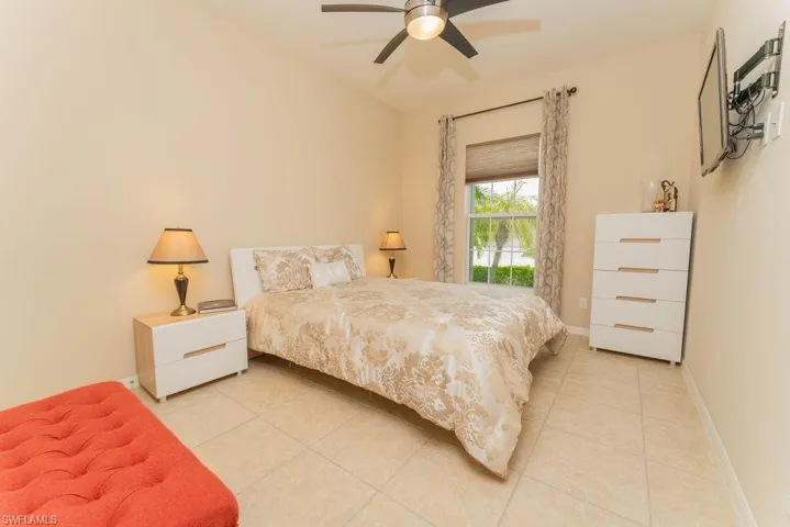 Bedroom with light tile patterned flooring, baseboards, and ceiling fan