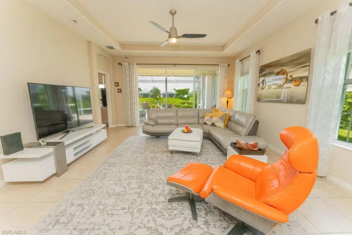 Living room featuring tile patterned flooring, a tray ceiling, and a ceiling fan