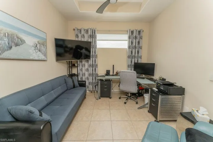 Office with light tile patterned flooring and a raised ceiling