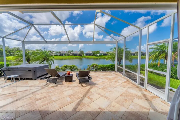 View of patio / terrace featuring a hot tub, glass enclosure, a water view, and a fire pit