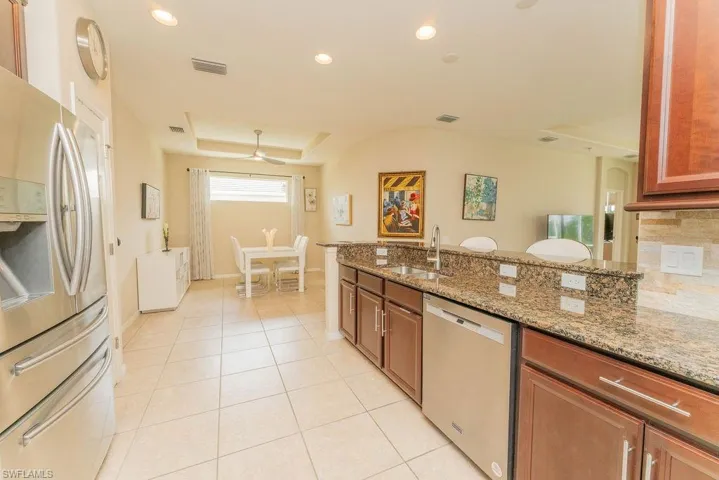 Kitchen with stainless steel appliances, light tile patterned floors, a sink, light stone countertops, and recessed lighting