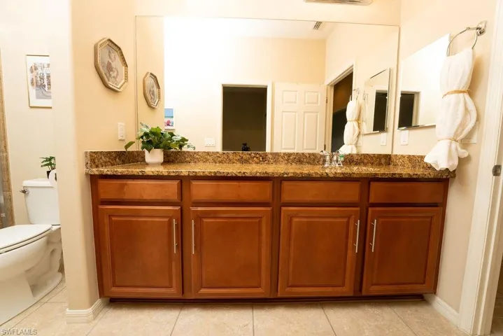 Full bath featuring toilet, vanity, tile patterned flooring, and baseboards