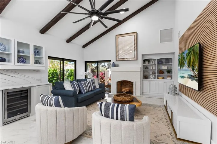Sliders out to the side patio, beverage fridge, cozy fireplace, and built-in book shelves!