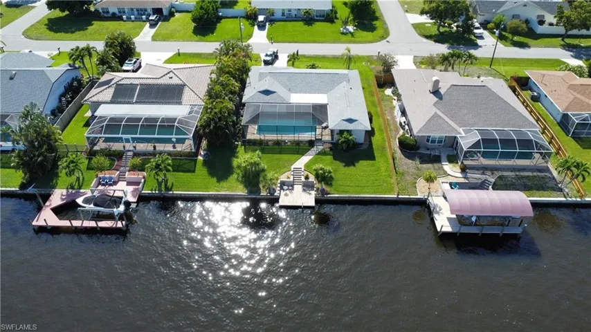 This property features a private boat dock with direct water access, a screened-in pool area, and a well-maintained lawn