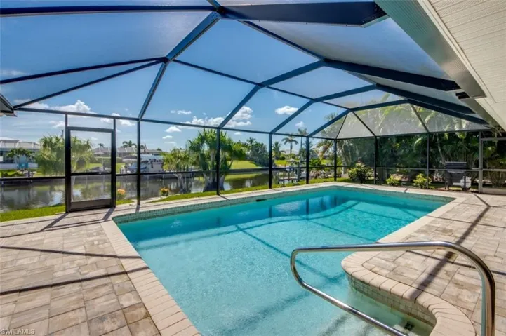 The property features a screened-in swimming pool and spa with a paver deck